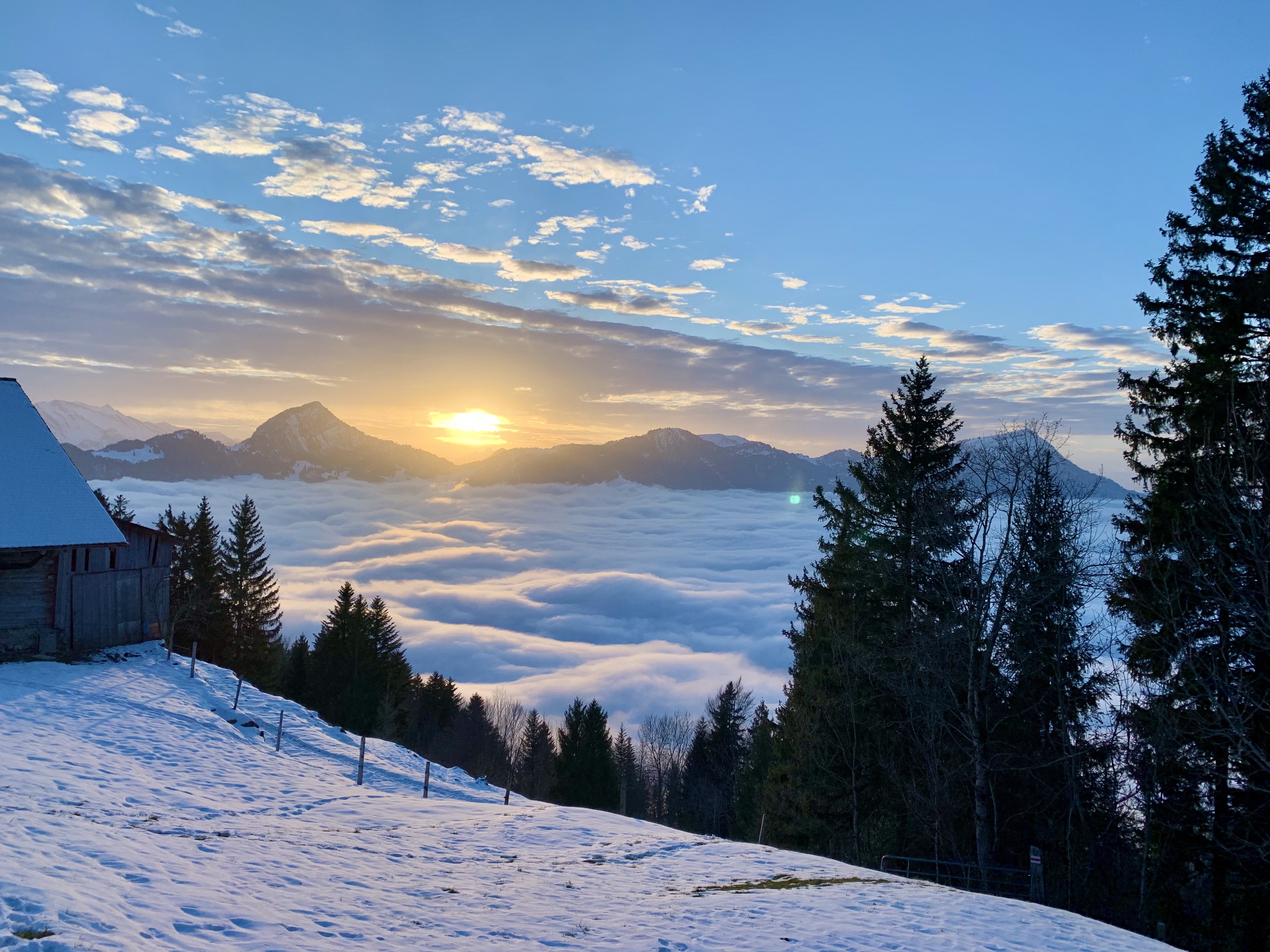 Winterliche Aussicht auf das Nebelmeer und die untergehende Sonne. 