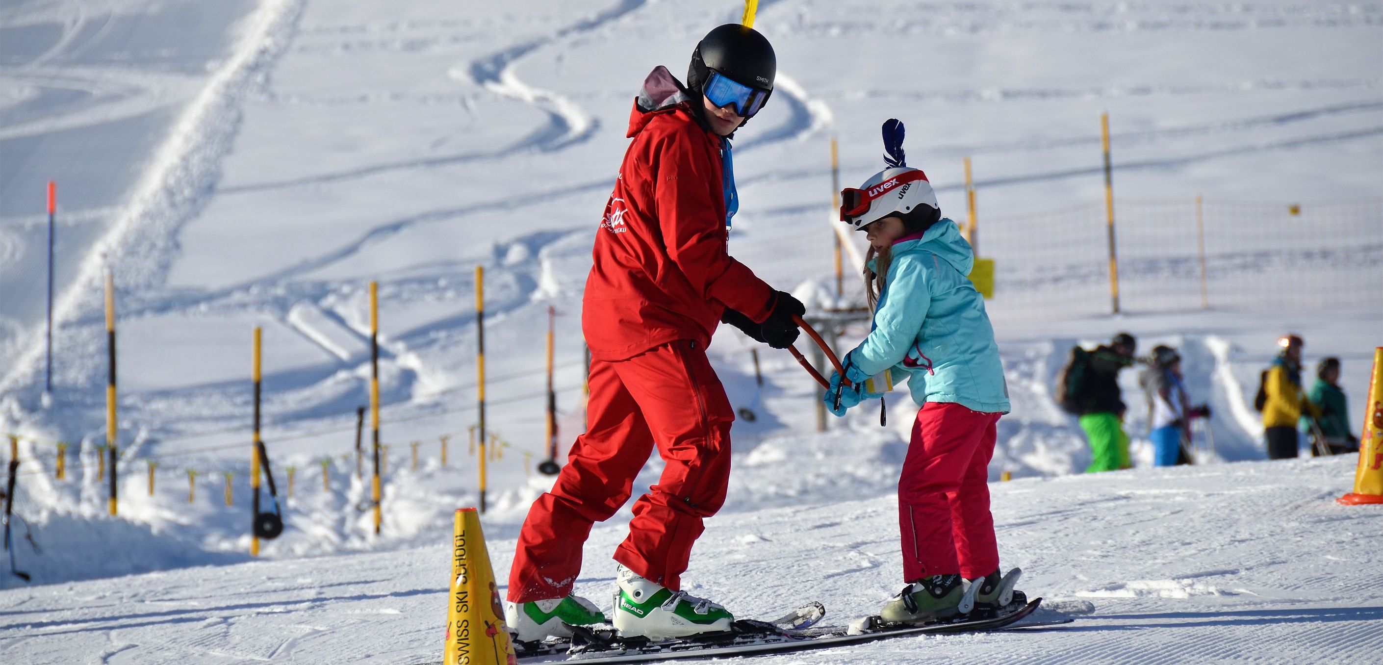 Skilehrer in rot mit Kind am Übung machen im Kinderland. 